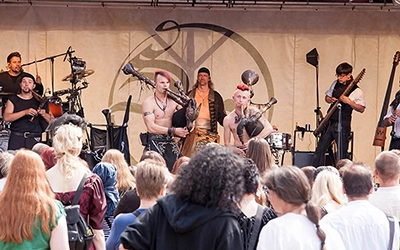 Die dynamische Live-Performance der Mittelalter-Rock-Band Saltatio Mortis während eines Festivals in Bückeburg, mit Mitgliedern und Dudelsäcken im Vordergrund. Fotografiert von Michael Schalansky.